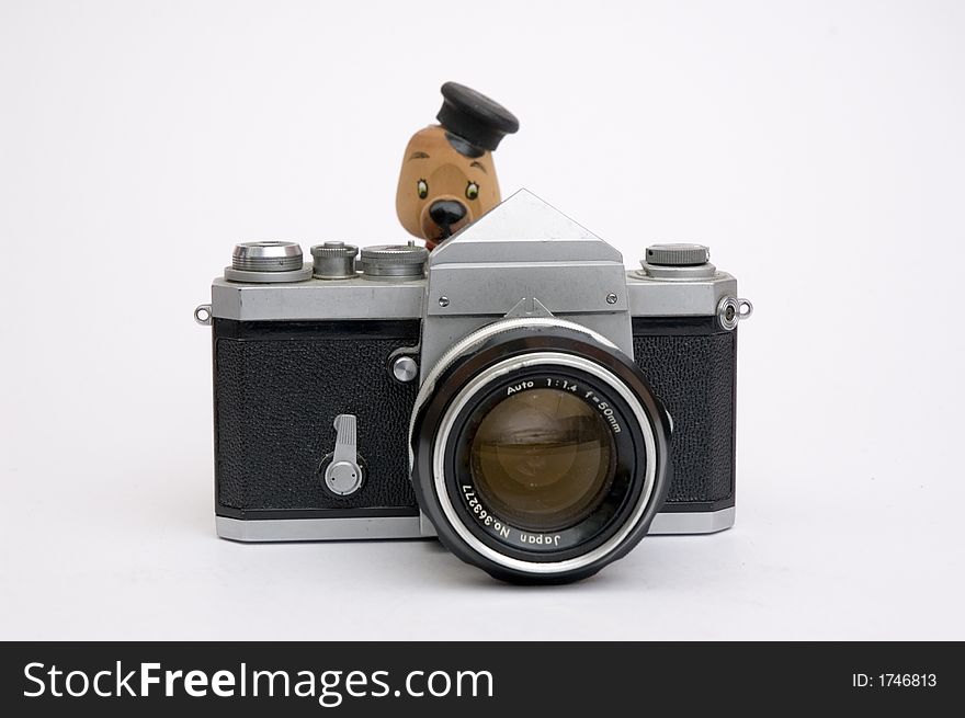 Vintage 35 mm camera pointing at viewer with a small wood model bear as photographer. Vintage 35 mm camera pointing at viewer with a small wood model bear as photographer