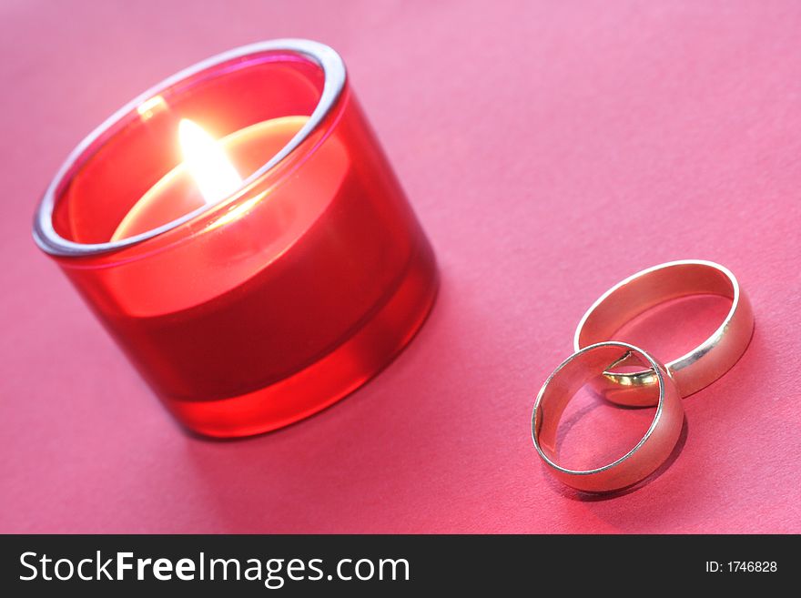 Gold wedding rings with red burning candle. Gold wedding rings with red burning candle
