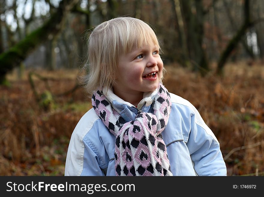 A little girl in a forest smiling. A little girl in a forest smiling