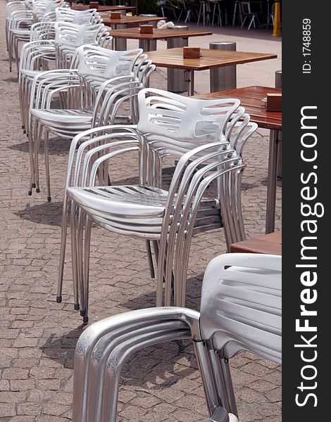 Stacked Silver Chairs In A Row At An Outdoor Restaurant