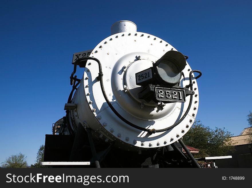 The front view of a vintage steam locomotive with a clear blue sky in the background. The front view of a vintage steam locomotive with a clear blue sky in the background