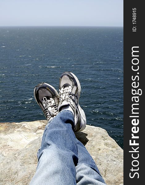 Relaxing On A Rock With Pacific Ocean View; Legs, Blue Jeans And Shoes