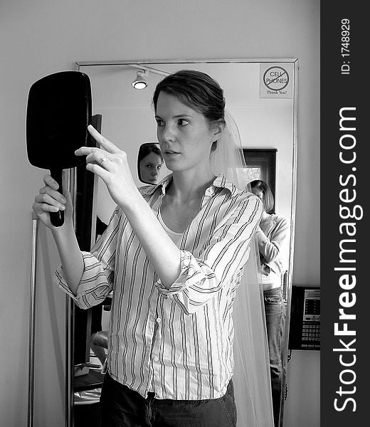 Bride Examining Her Reflection in Mirror With Veil At Beauty Salon. Bride Examining Her Reflection in Mirror With Veil At Beauty Salon