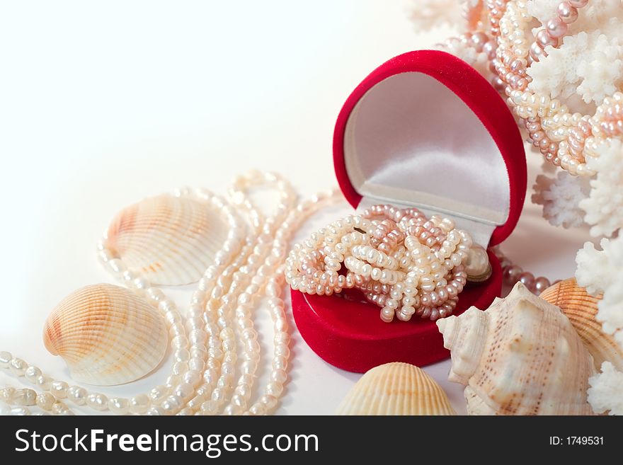 Shells, corals and heart-shaped red box with shiny pearl necklace. With copy space on white background. Shells, corals and heart-shaped red box with shiny pearl necklace. With copy space on white background.