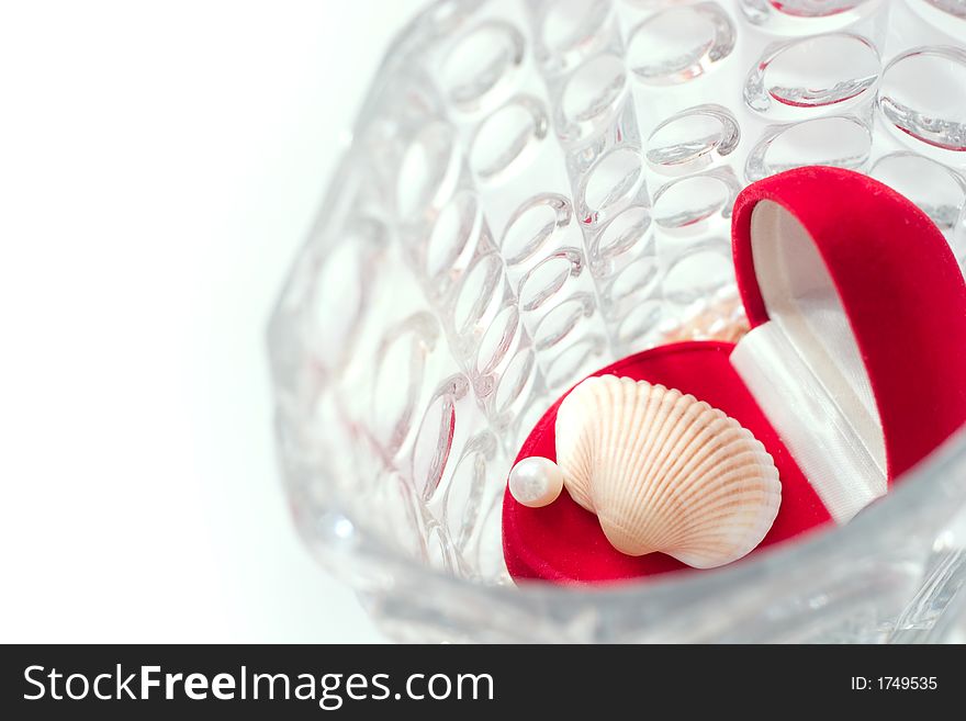Red box with white pearl and shell in a crystal vase. Focal point is on the pearl. Copy space is on the left side of image. Red box with white pearl and shell in a crystal vase. Focal point is on the pearl. Copy space is on the left side of image