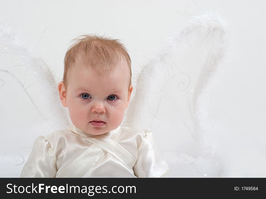 Cute little girl dressed like fairy with fluffy wings is crying. Cute little girl dressed like fairy with fluffy wings is crying