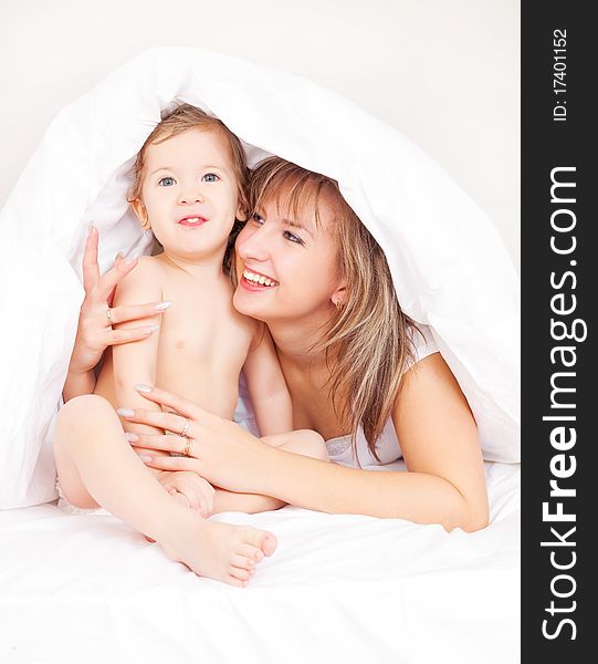Young beautiful mother and her baby on the bed at home after the shower (focus on the baby)