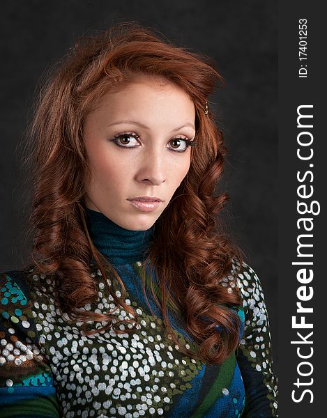 Young beautiful woman with long curly hairs. Dark background