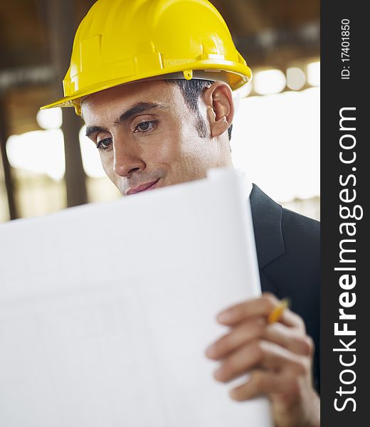 Caucasian male architect examining blueprint. Vertical shape, waist up, side view, copy space. Caucasian male architect examining blueprint. Vertical shape, waist up, side view, copy space