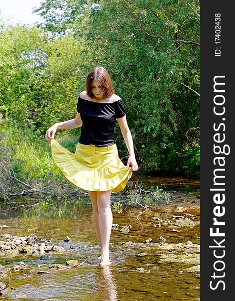 Young woman crossing little stream in forest. Young woman crossing little stream in forest