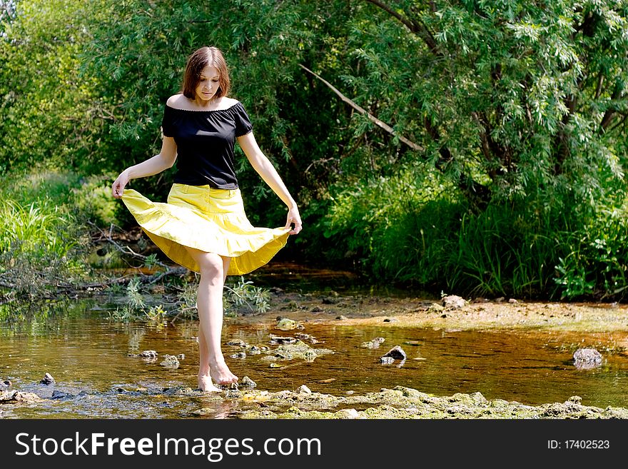 Young woman crossing little stream in forest. Young woman crossing little stream in forest
