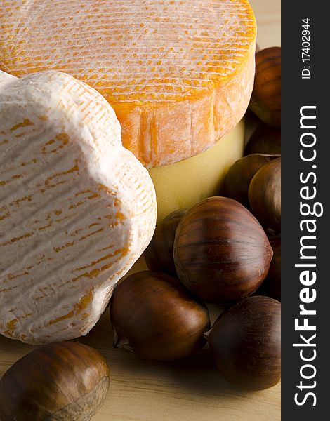 3 types of cheese on a wooden plate with hazelnuts. 3 types of cheese on a wooden plate with hazelnuts.