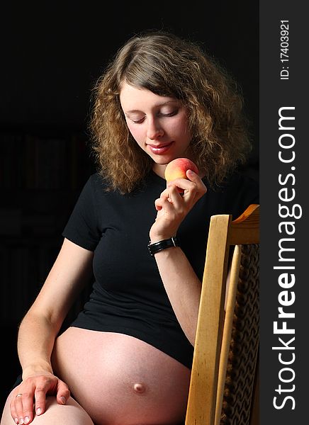 Happy young pregnant woman with peach