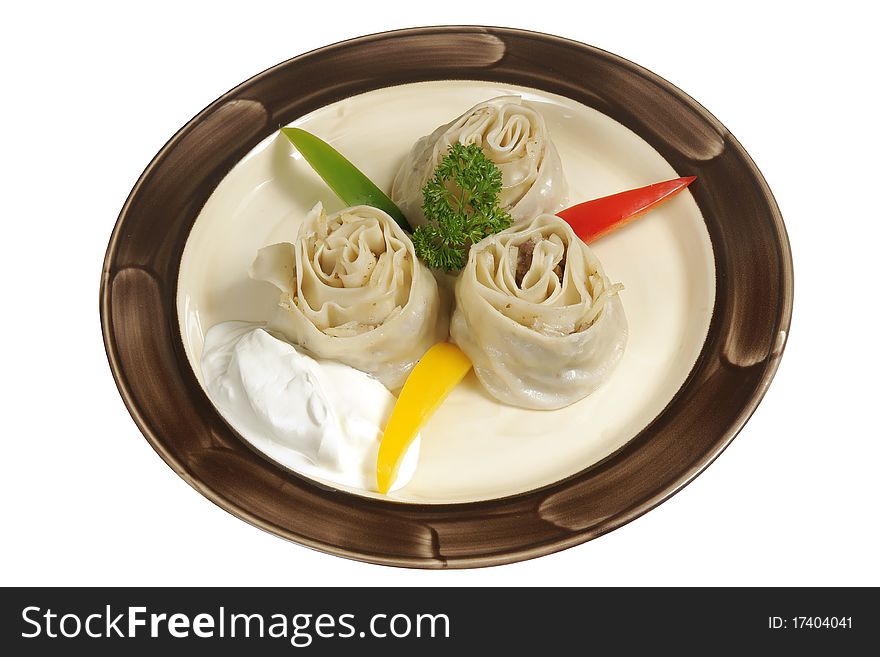 Oriental meat dumplings, sour cream, sweet pepper and parsley on white plate with brown band. Oriental meat dumplings, sour cream, sweet pepper and parsley on white plate with brown band