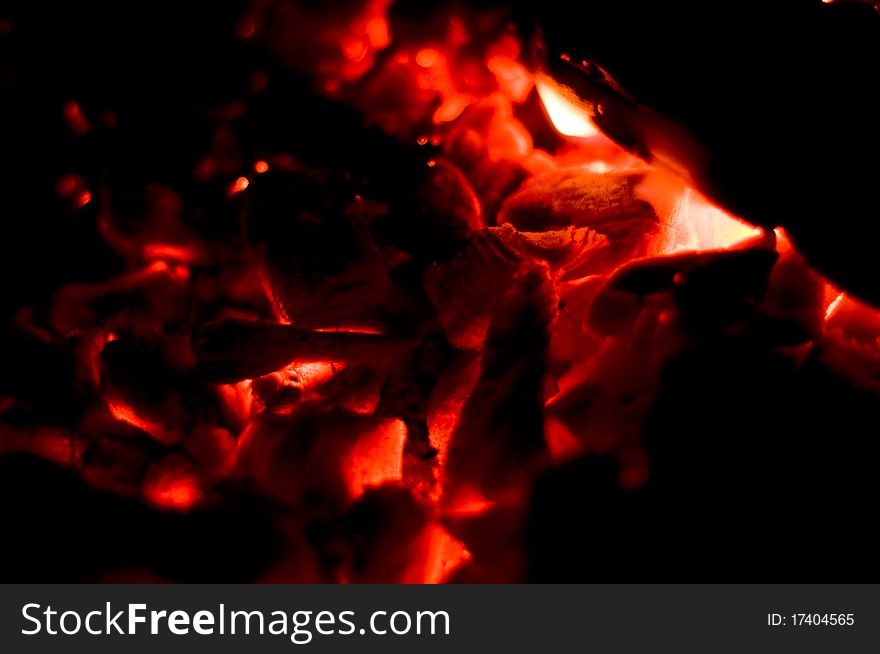 Coals flicker on a burning down fire