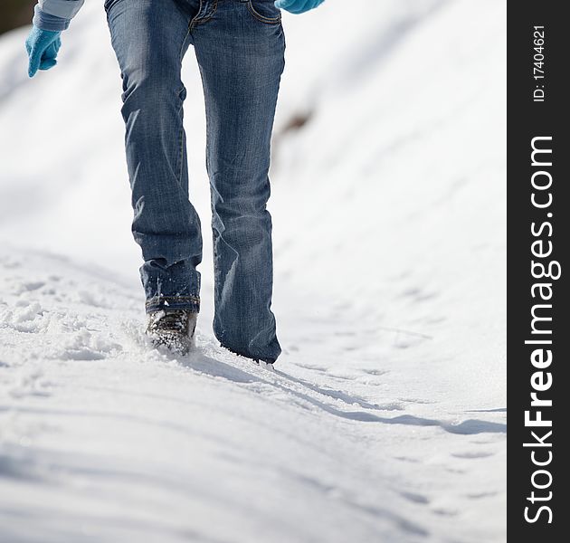 Pretty young woman walking in deep snow on a sunny winter day