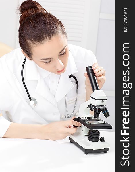 Female medical doctor working with a microscope. Female medical doctor working with a microscope