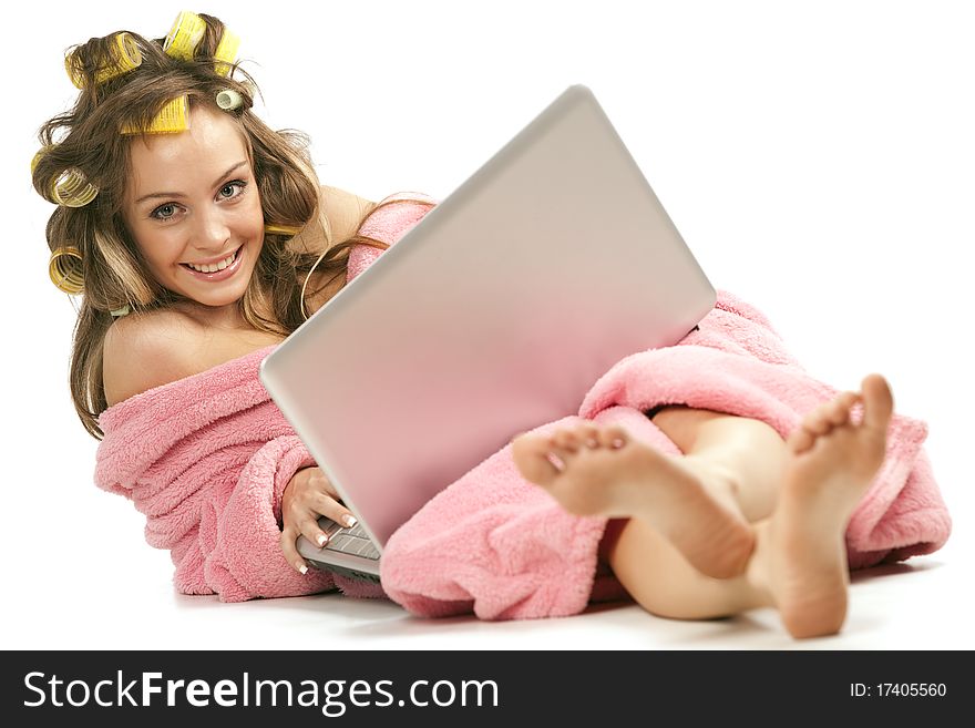 Young adult girl in pink dressing gown and with hair rollers sitting with laptop. Young adult girl in pink dressing gown and with hair rollers sitting with laptop