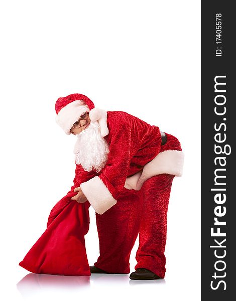 Funny Santa Clause carrying a heavy sack with gifts. Isolated on white.