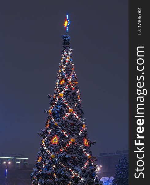 Christmas tree decorated with show on branches and garlands of night