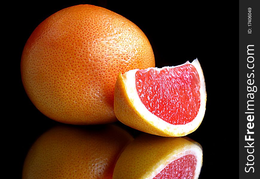 Grapefruit with segment and mirror isolated on black. Grapefruit with segment and mirror isolated on black