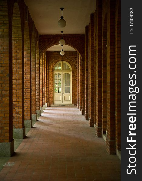 A hallway of a red brick building with sunlight shining in from the left. A hallway of a red brick building with sunlight shining in from the left.