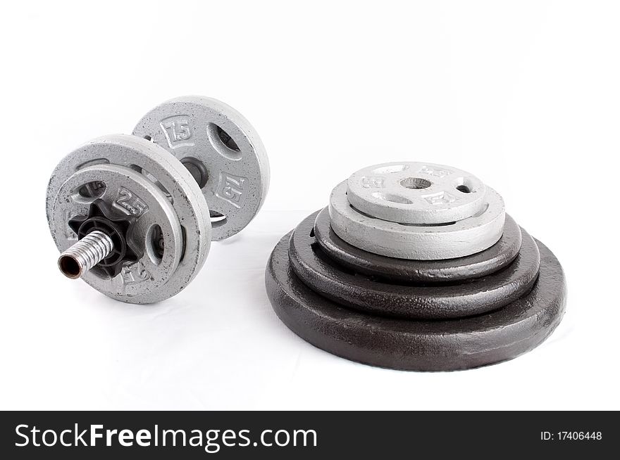 Different iron disc weights unit (plates) and Dumbbells isolated on white. Different iron disc weights unit (plates) and Dumbbells isolated on white