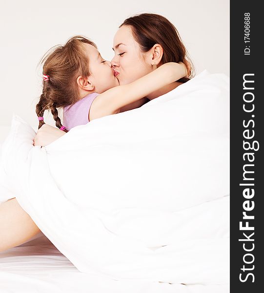 Beautiful young mother and her five year old daughter on the bed at home. Beautiful young mother and her five year old daughter on the bed at home