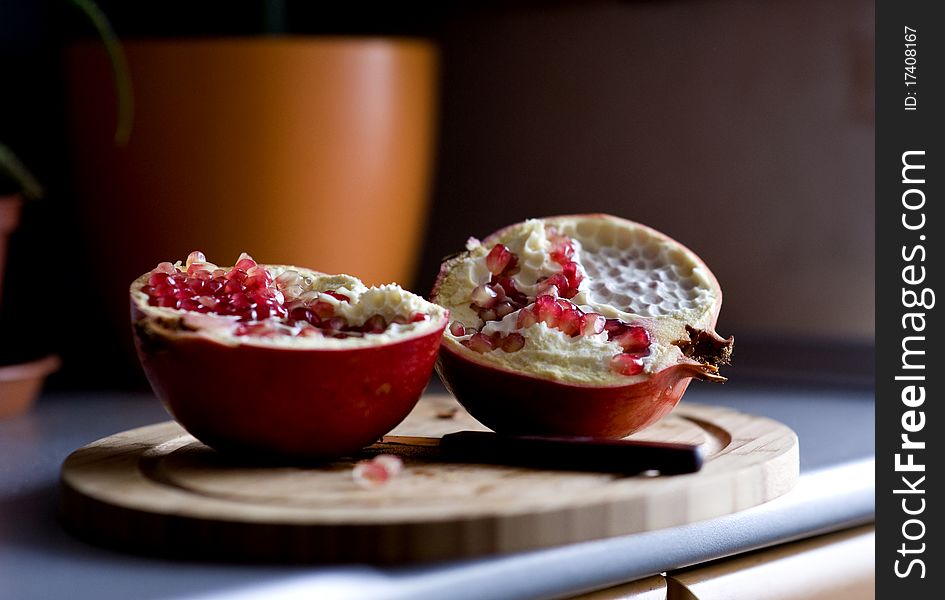 Two halves of pomegranate on the cutting board