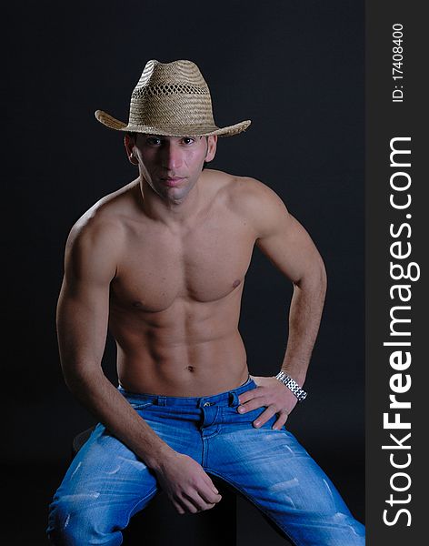 Sexy young male isolated against black wearing straw hat low key. Sexy young male isolated against black wearing straw hat low key