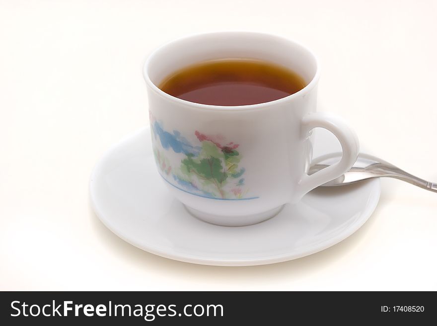 Strong black tea in a cup on the saucer on a white background closeup