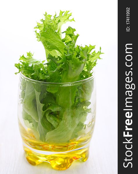 Fresh lettuce leaves in glass on white background