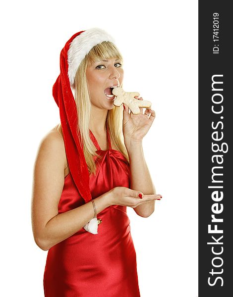 Beautiful girl in a red dress and hat Santa with gingerbread men. Tries to bite him. Isolated on a white background. Beautiful girl in a red dress and hat Santa with gingerbread men. Tries to bite him. Isolated on a white background