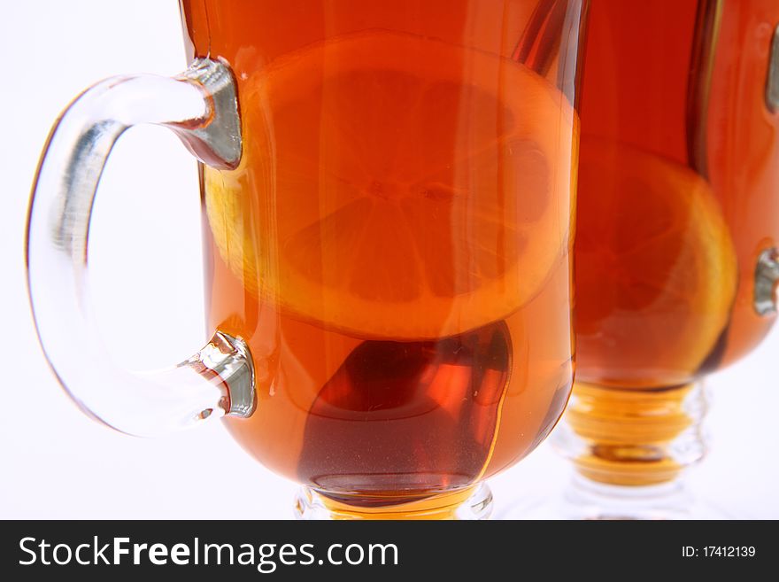 Two glasses of tea with lemon on white background