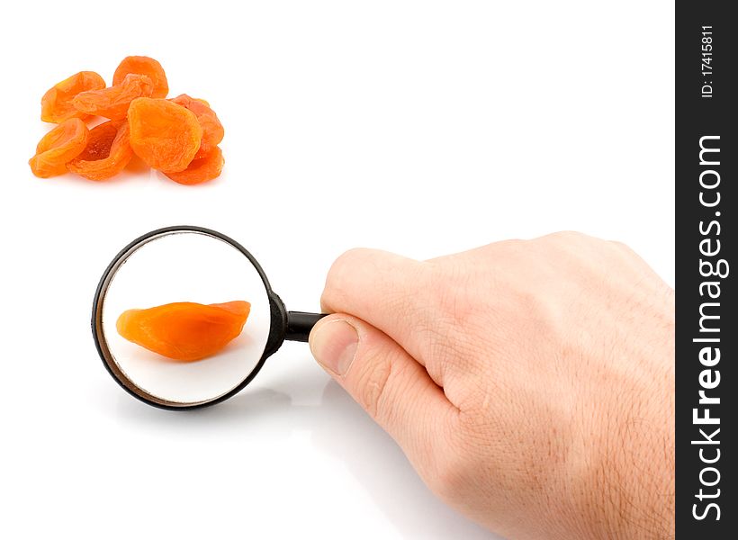 Dried apricots under a magnifying glass on a white background. Dried apricots under a magnifying glass on a white background.