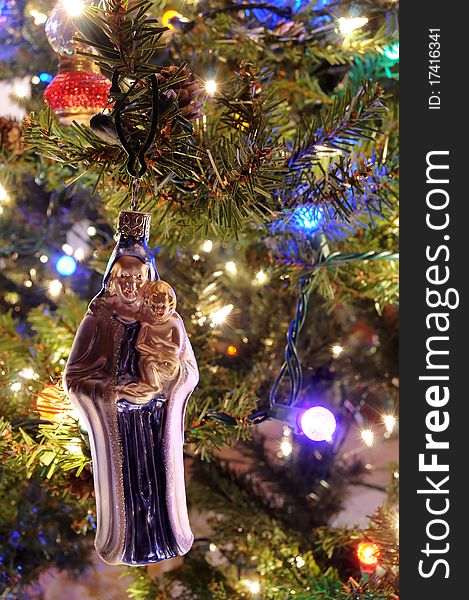 Christmas Ornament of Mary and Jesus hanging on a Christmas Tree with lights. Christmas Ornament of Mary and Jesus hanging on a Christmas Tree with lights