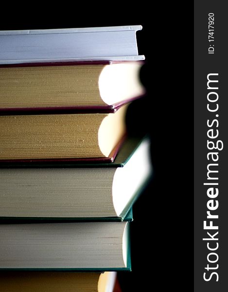 Old books stacked on each other on a black background