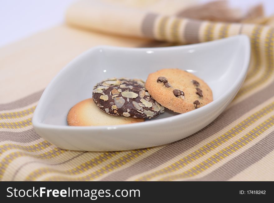 Delicious cookies and biscuits on white plate and color background