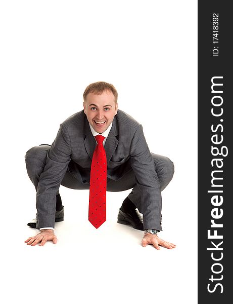 Man in gray suit and red tie sits in pose to frog