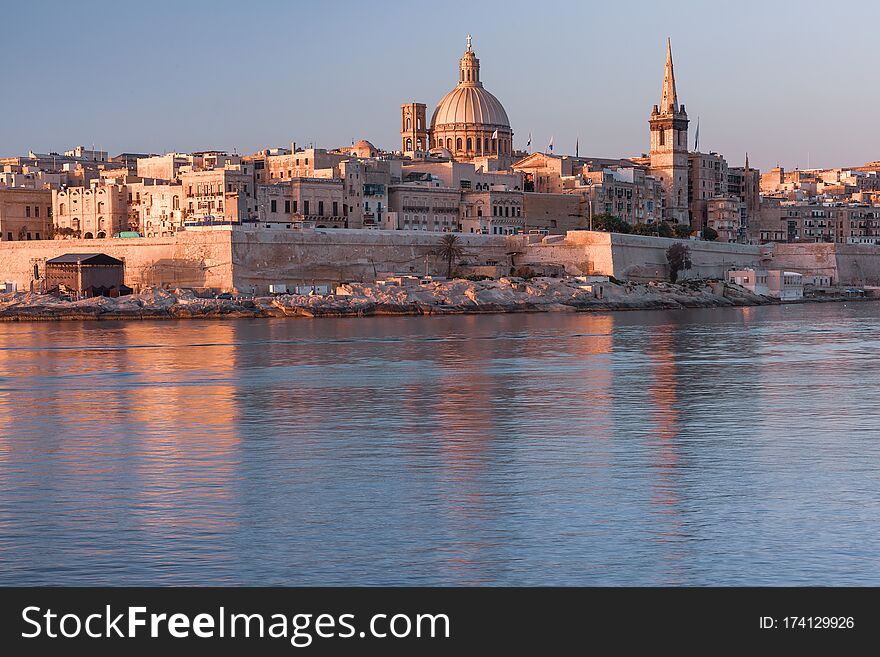 Valletta with Our Lady of Mount Carmel church and St. Paul`s Anglican Pro-Cathedral at sunrise as seen from Sliema, Valletta, Malta. Valletta with Our Lady of Mount Carmel church and St. Paul`s Anglican Pro-Cathedral at sunrise as seen from Sliema, Valletta, Malta