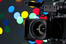 Modern Video Camera Against Blurred Colorful Lights Stock Photo
