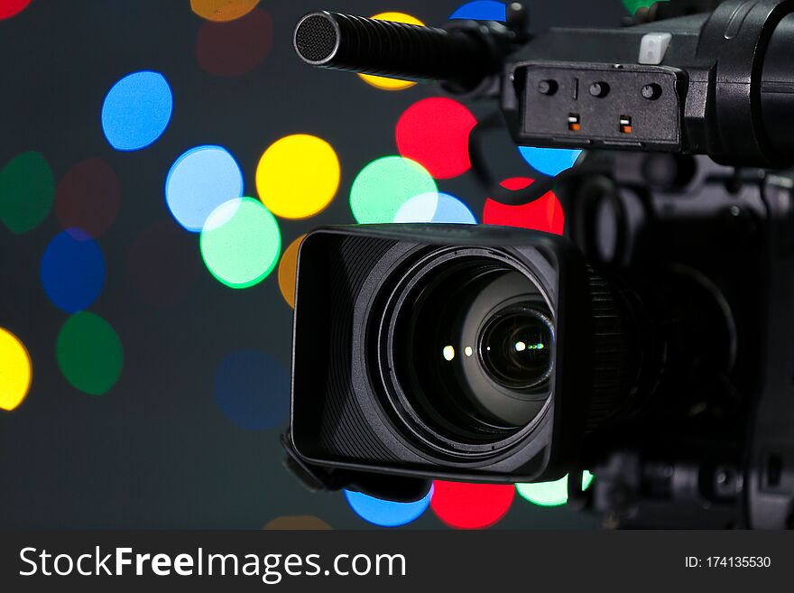Modern Video Camera Against Blurred Colorful Lights