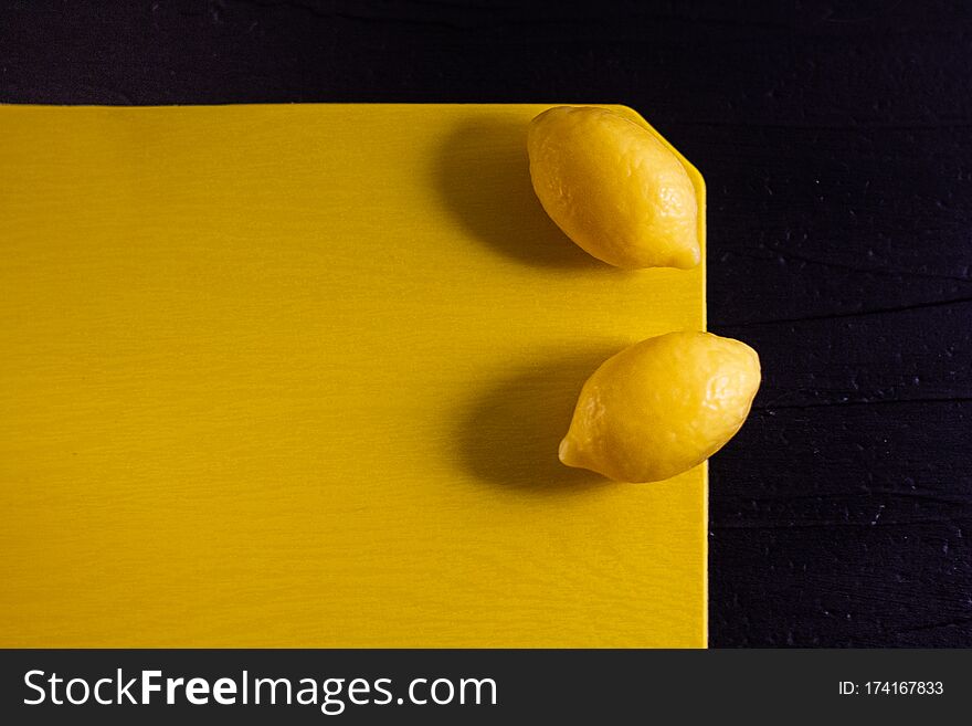 Minimalism photo of two yellow small fresh lemons soap with shadows on monochrome yellow and black background. Top view, copy space. Minimalism photo of two yellow small fresh lemons soap with shadows on monochrome yellow and black background. Top view, copy space.