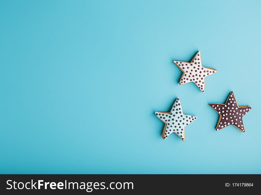 Close-up Of Three Homemade Glazed Gingerbread Cookies Made In The Form Of Stars On A Blue Background. Handmade Cookies. Free Space