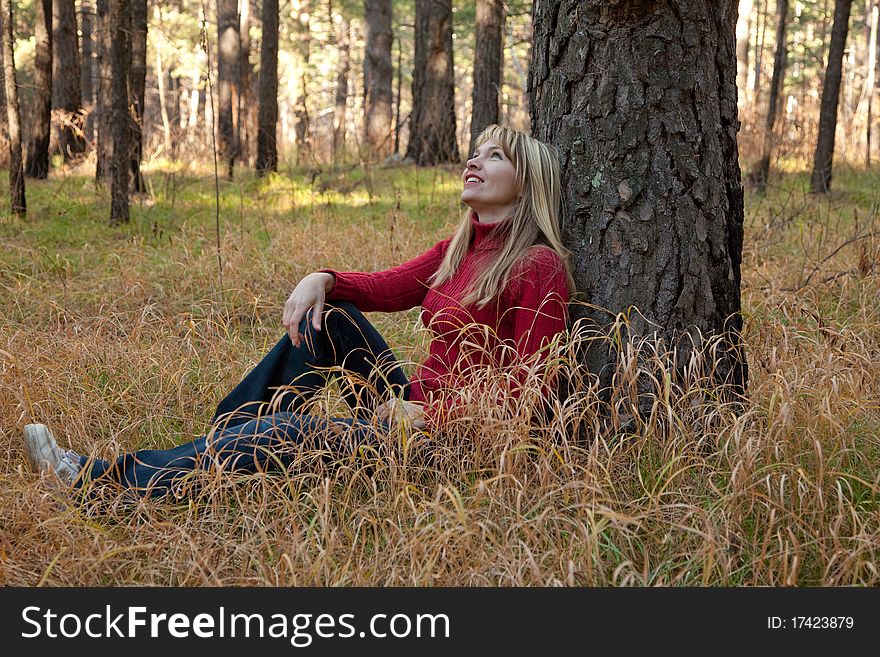 Smiling woman sits near tree