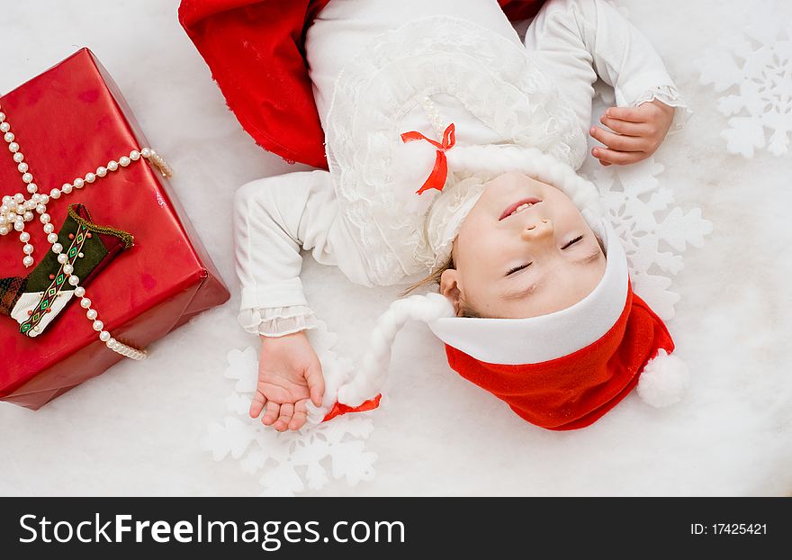 The little girl sleeps near to a New Year's gift. The little girl sleeps near to a New Year's gift