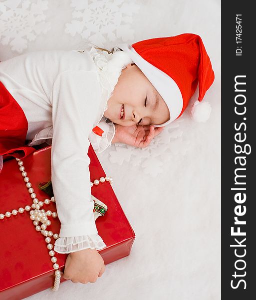 The little girl sleeps near to a New Year's gift. The little girl sleeps near to a New Year's gift