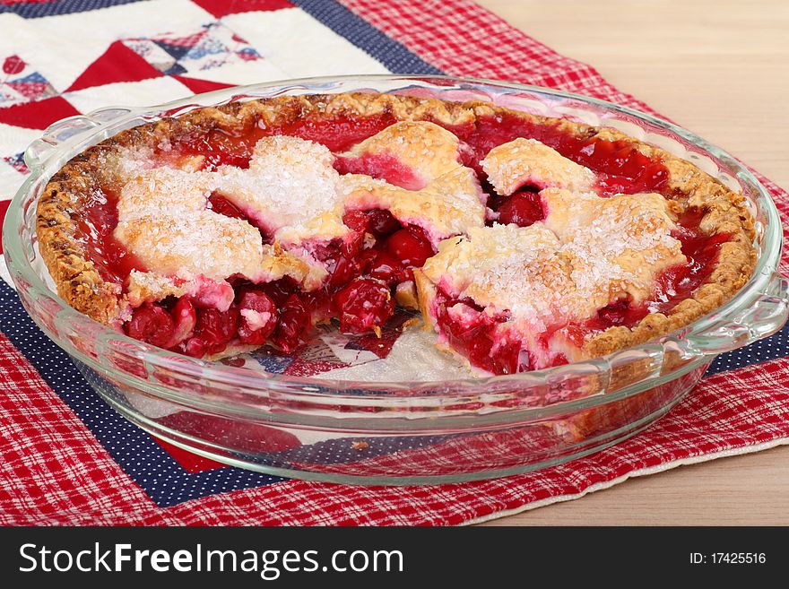 Whole cherry pie with a slice cut out in a baking dish