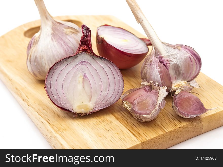 Garlic and onion on a wooden plate on white