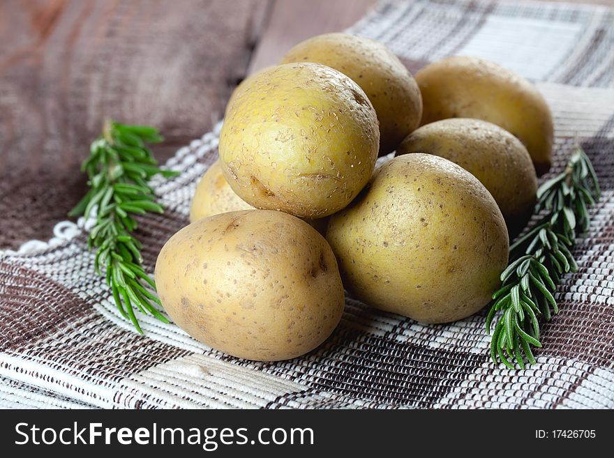 Fresh potatoes with rosemary on dishtowel. Fresh potatoes with rosemary on dishtowel